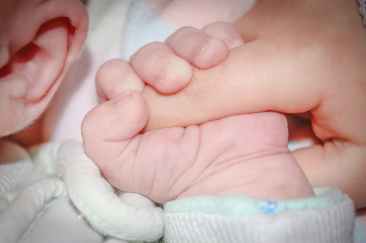 baby holding human index finger